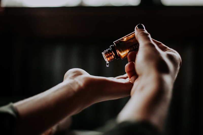 Close-up of hands dispensing a drop from a small amber glass bottle into an open palm